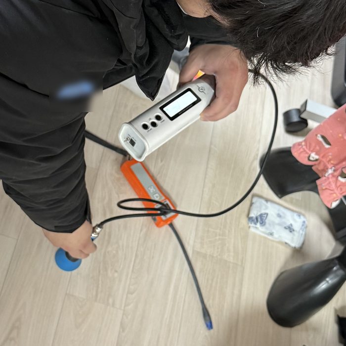실내 바닥에서 탐지 장비로 누수 위치를 확인하는 모습